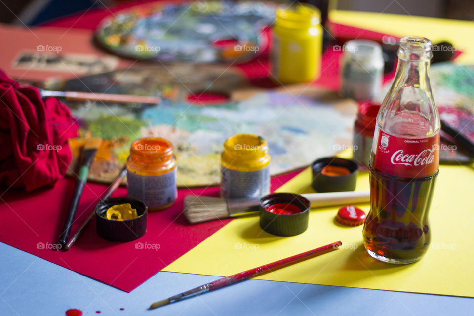 Coca-Cola bottles and colorful painting materials on the table