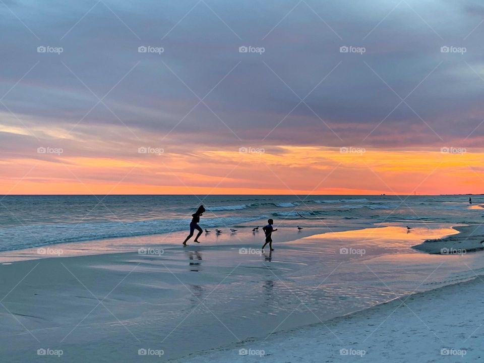 Kids having fun. Crisp, white sand meets the deep blues of the Gulf of Mexico during a magnificent sunset