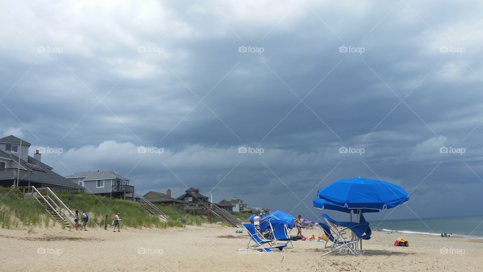 Approaching storm at the beach with homes and umbrellas