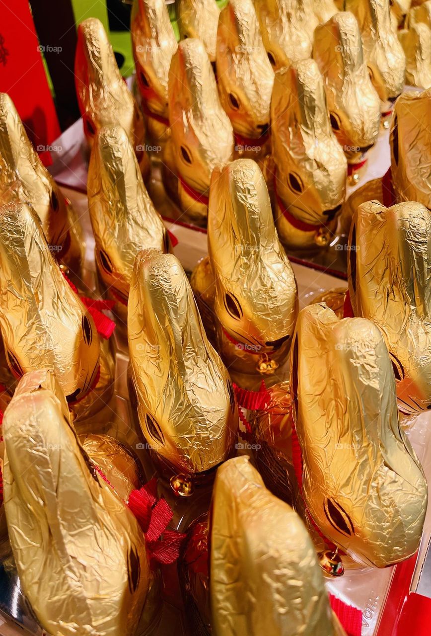 bunny-shaped chocolates wrapped in gold foil and decorated with a red ribbon and a bell