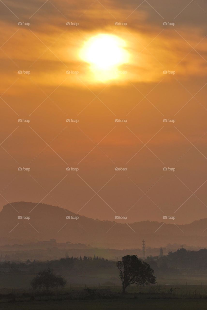 Sol matinal sobre un paisaje con profundidad entre nieblas y tonos ocres.