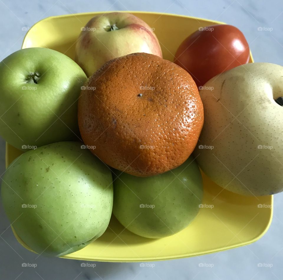 Healthy fruits apples Tomato’s orange on yellow  bowl white  background 