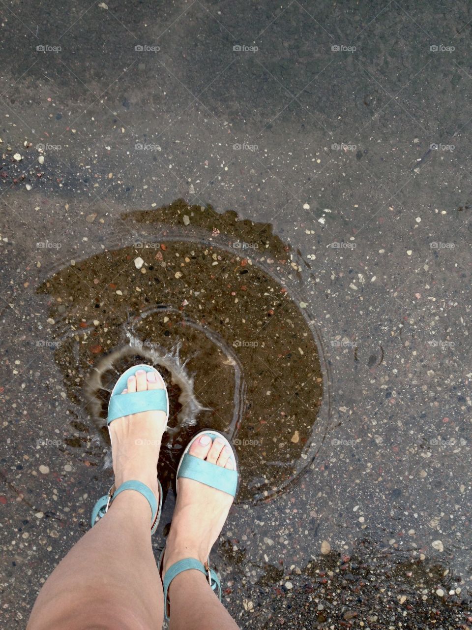 Green sandals in puddle and water splash 