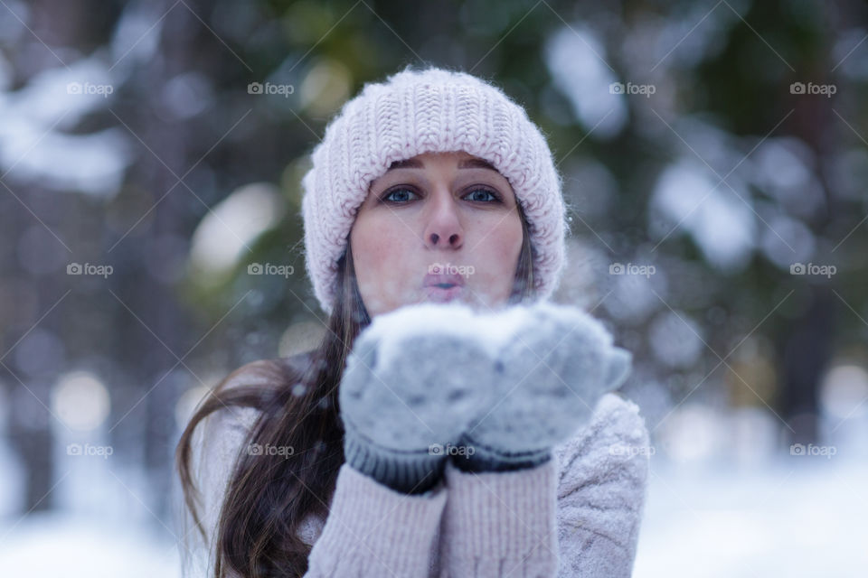 Woman blowing on snow in forest 