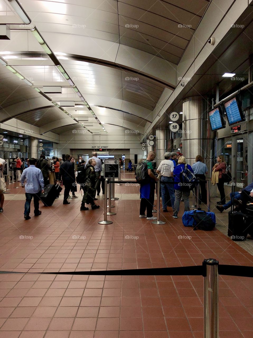 Travelers hustling and bustling through the concourse at South Station Bus Terminal in Boston, MA, while several passengers line up with their luggage to board a bus to adventures unknown.