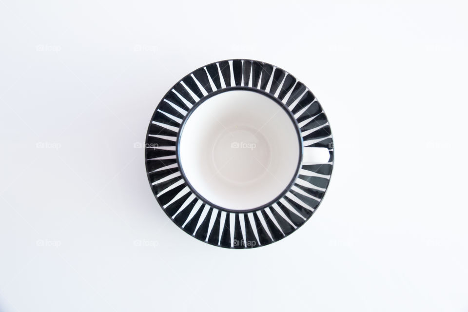Black and white striped cup with saucer on white background , from above 