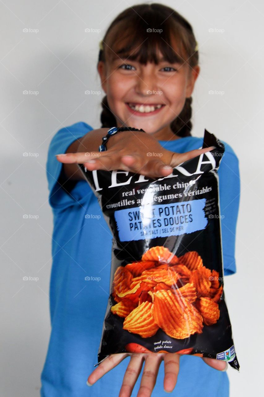 Cute happy girl with a bag of chips