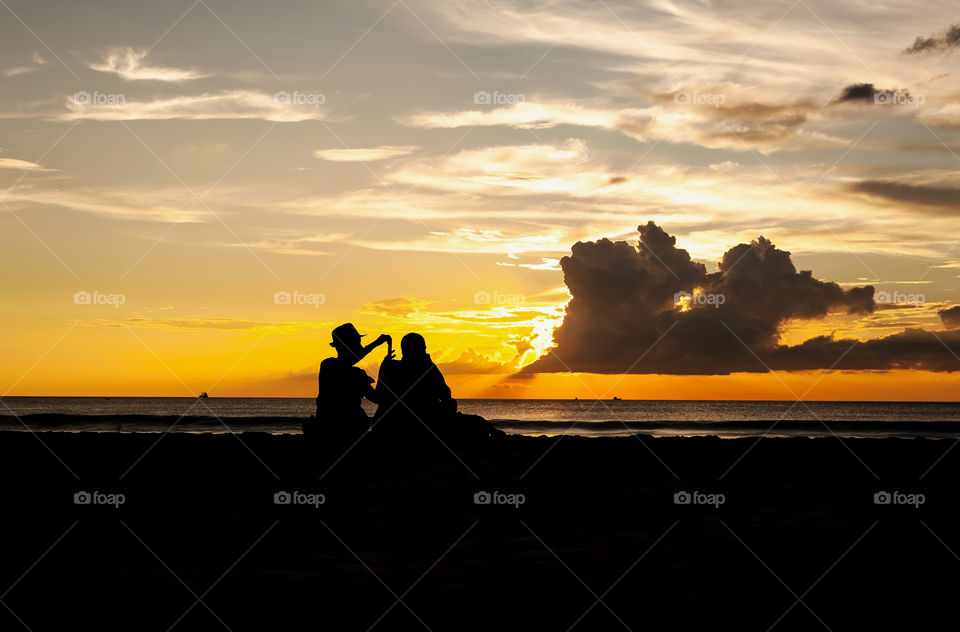 Silhouetted couple relax on the beach