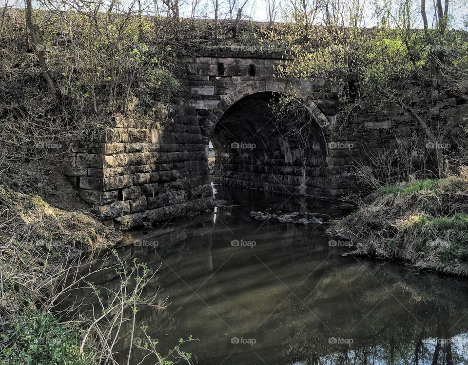 Historic stone arch bridge hidden in the woods built ca. 1880 for the railroad. 