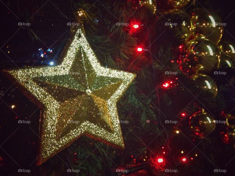 Gold plastic star, balls, red lights garland and other Christmas decorations on artificial fir tree in Moscow, Russia