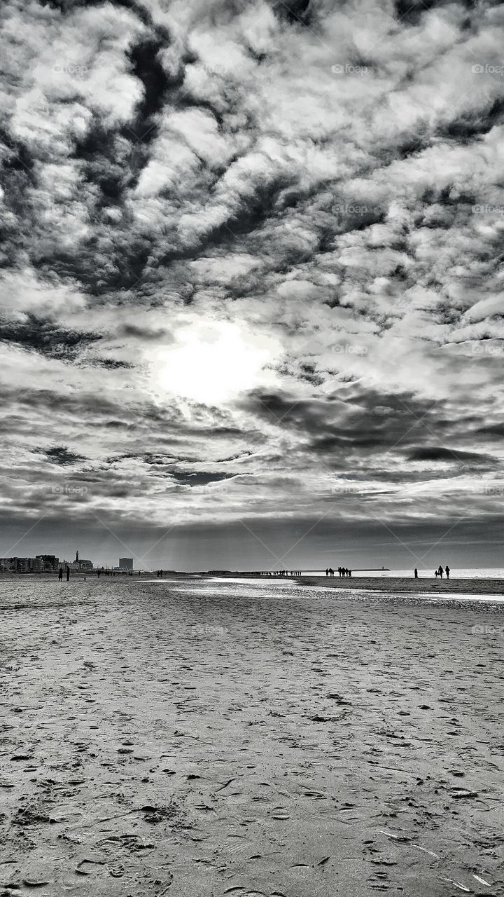 The sun piercing through the clouds above Scheveningen beach.