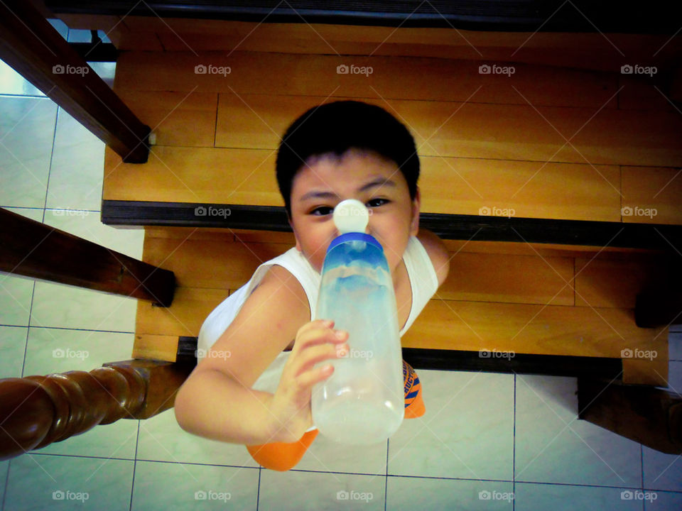 asian child sitting on stairs and drinking water