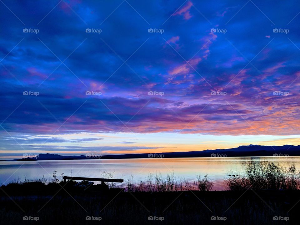 beautiful sunset reflecting off the lake and making siluettes