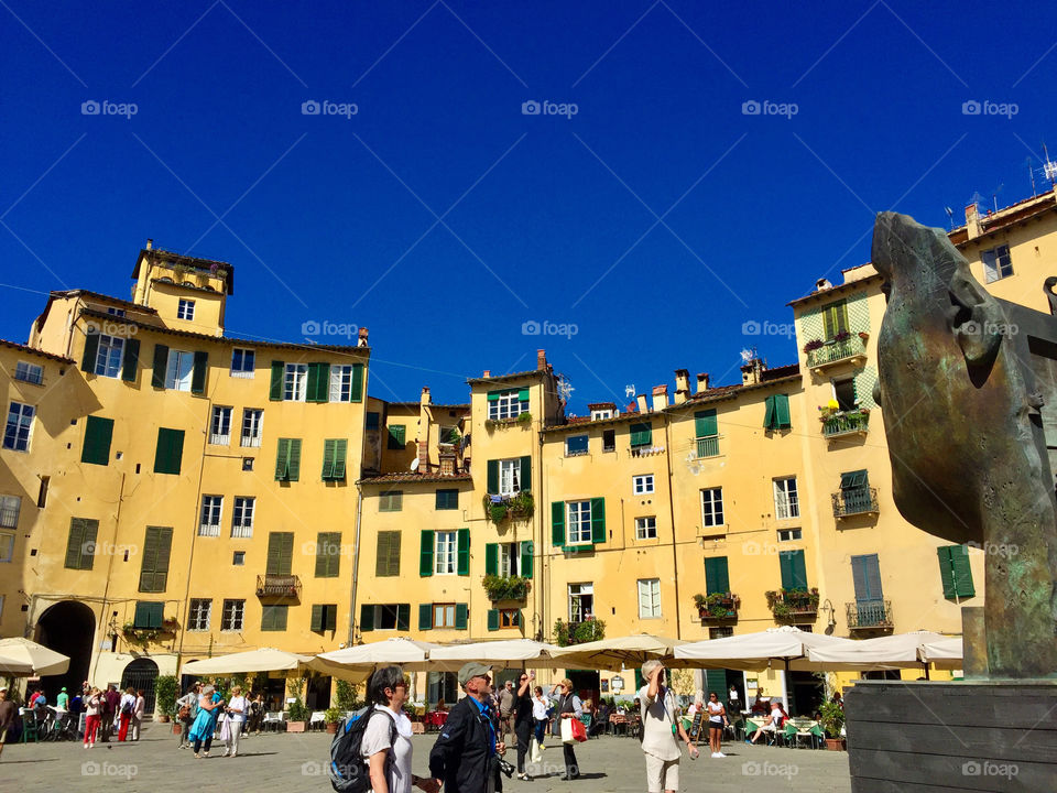 Village piazza in Italy with yellow buildings and deep blue sky 