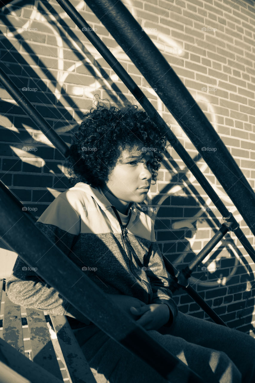 Young Boy Sits On Steps In Urban Neighborhood in Richmond, Virginia USA