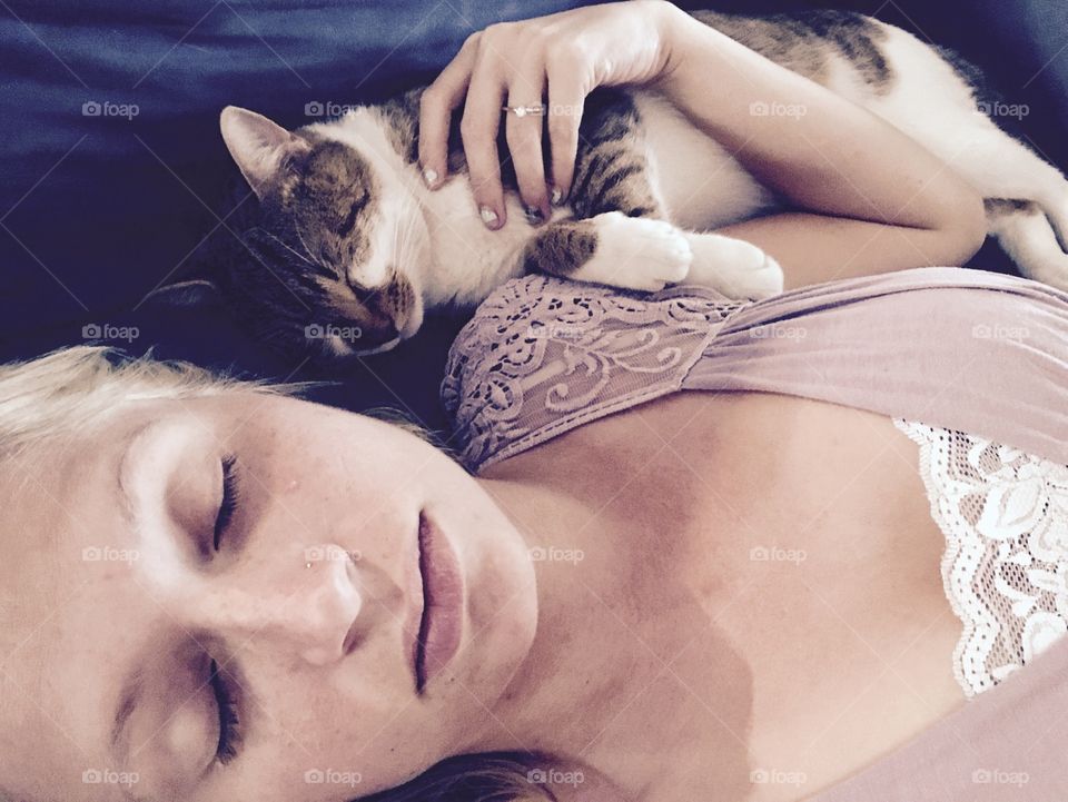 Cat sleeping on bed with woman