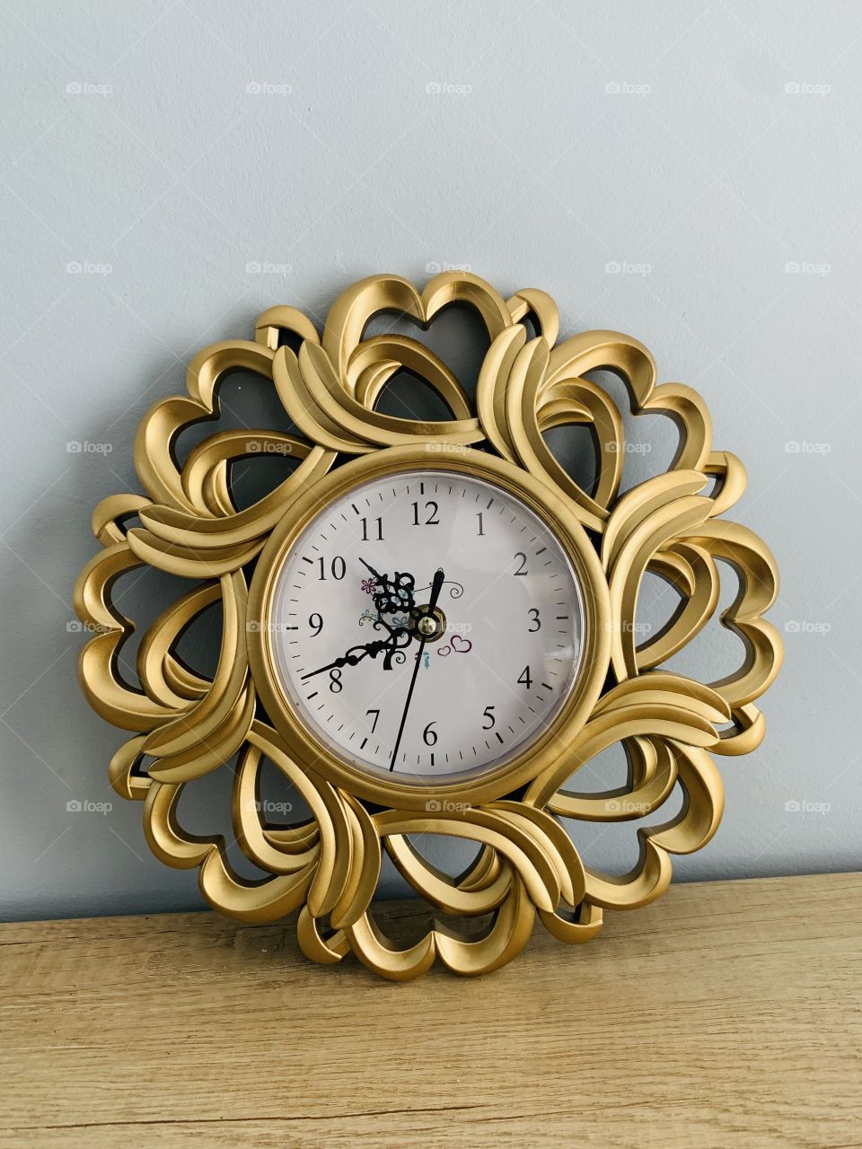 A gold nonfunctional wall clock on a cream counter against a wall in a house. 