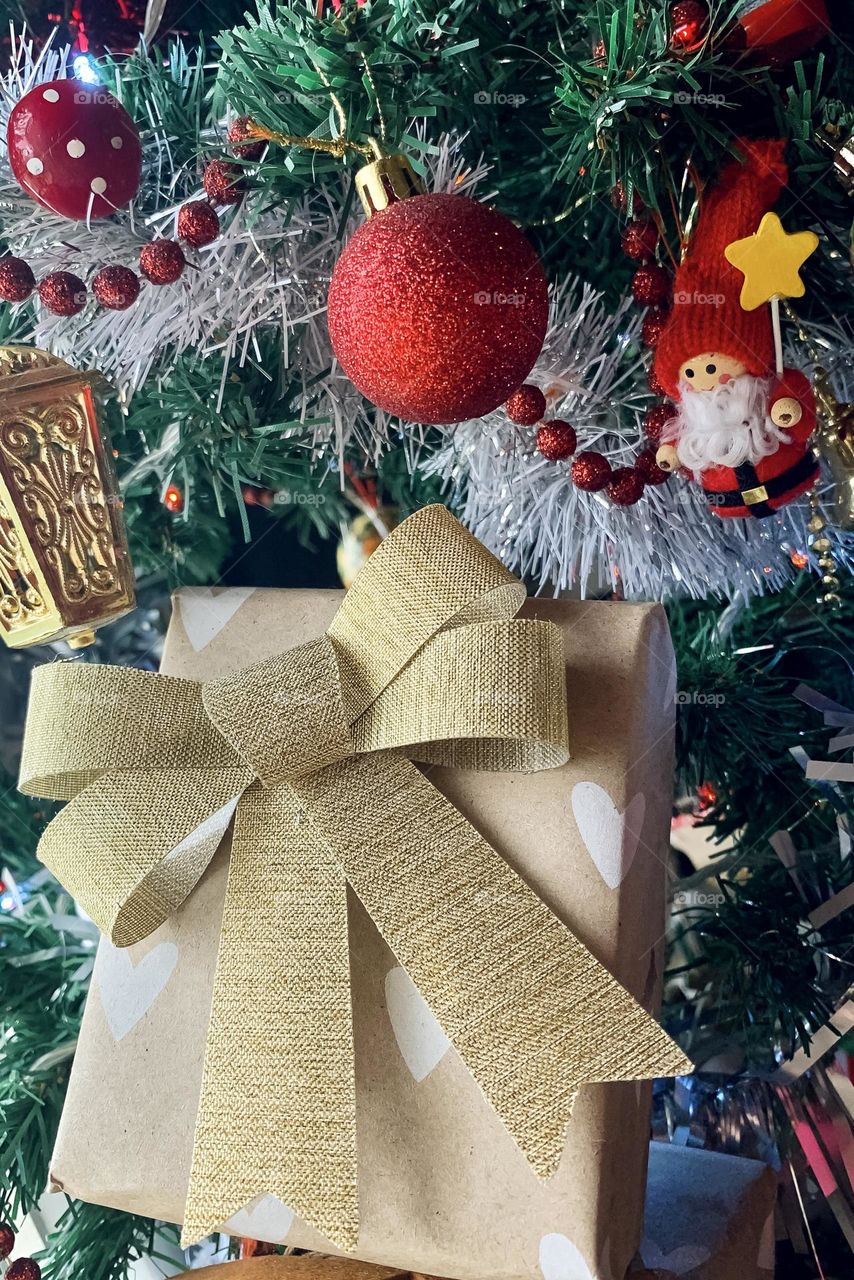 A wrapped gift sits amid the decorations on a Christmas tree 