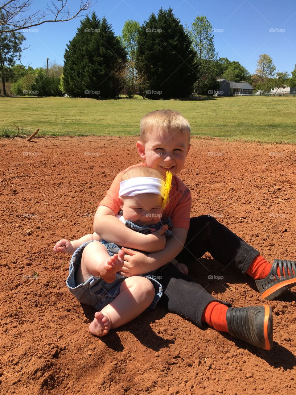 Cute boy holding his sister at outdoors