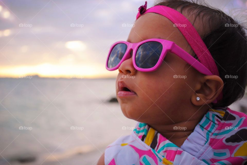 A little girl with pink hair band with sunglasses
