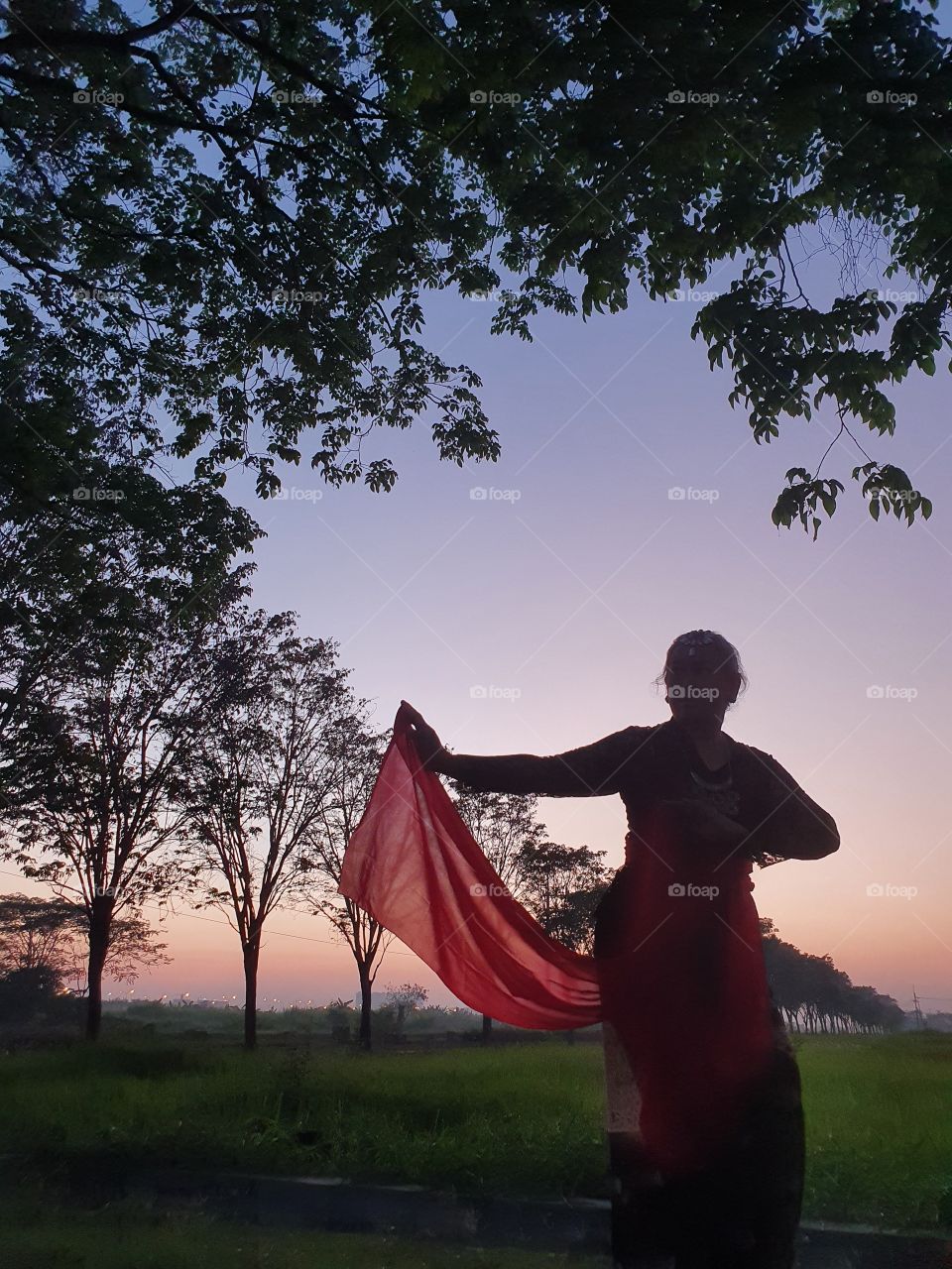 A woman wearing a kebaya is dancing in a shawl when the sun is about to rise