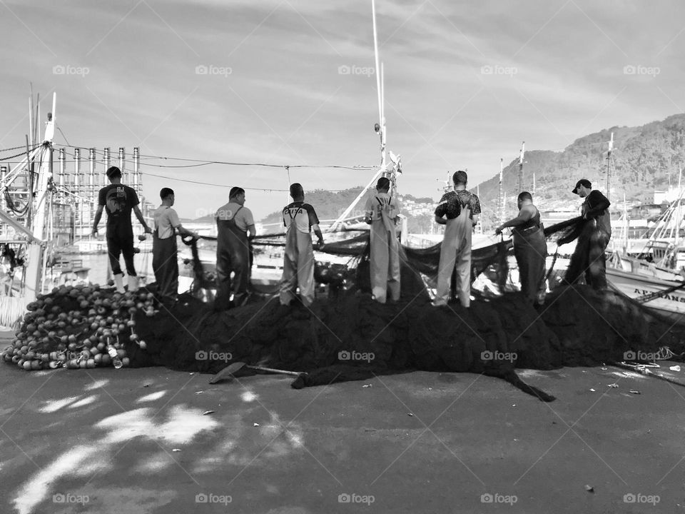 group of fishermen collecting the fishing net at the port in Angra dos Reis, Rio de Janeiro, Brazil