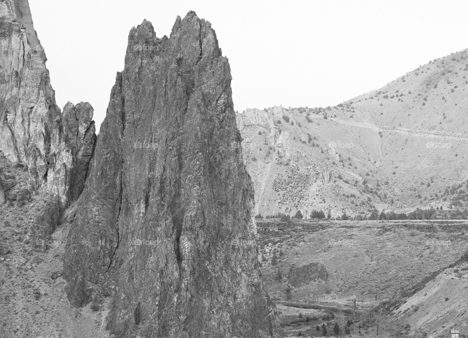 The rugged and steep Smith Rocks and surrounding hills in Central Oregon on an overcast summer day. 
