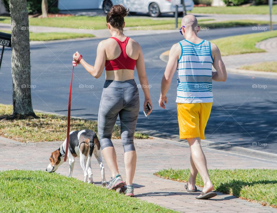 Two adults walking dog in exercise outfits