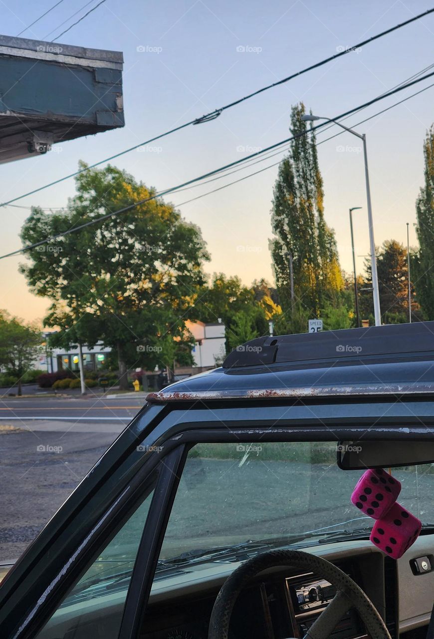 sunset view through car window with pink fuzzy dice while stopping for a roadside meal in Oregon