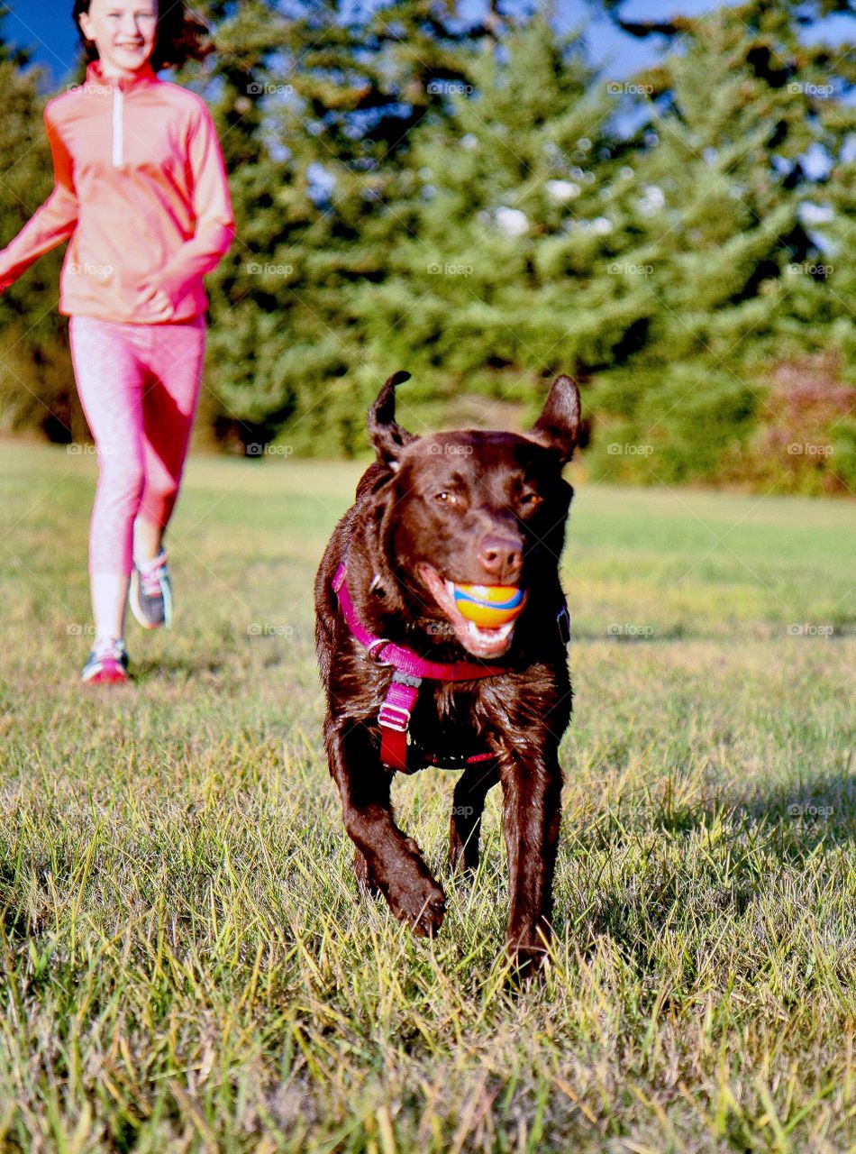 Girl running with dog in a springtime park