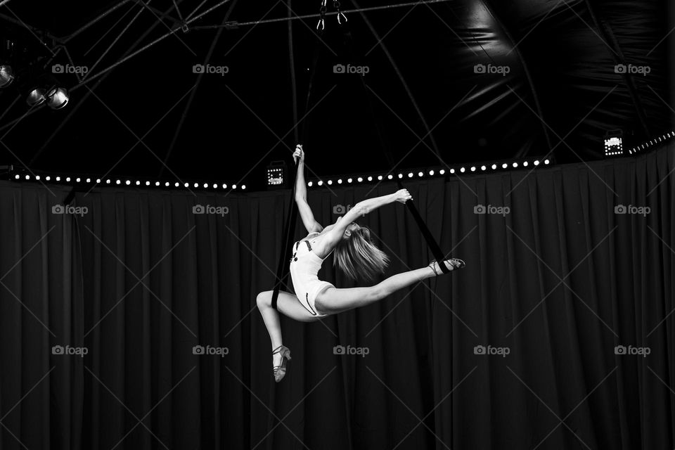 A black and white portrait of a circus entertainer performing a beautiful act on ropes, striking an elegant pose.