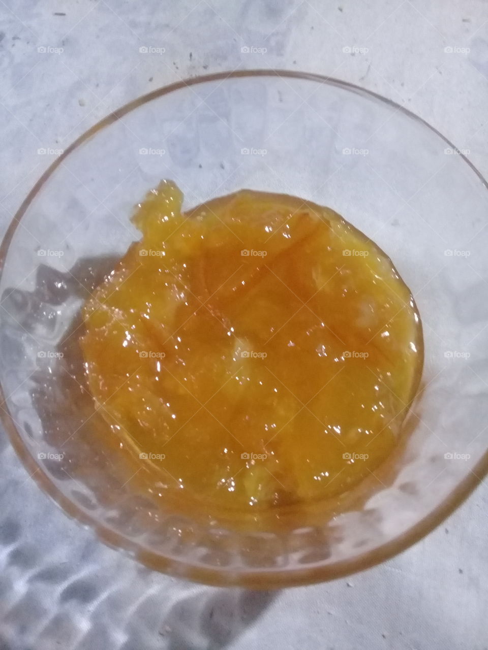 fotografía de una compotera de vidrio con una porción de mermelada de naranja casera.