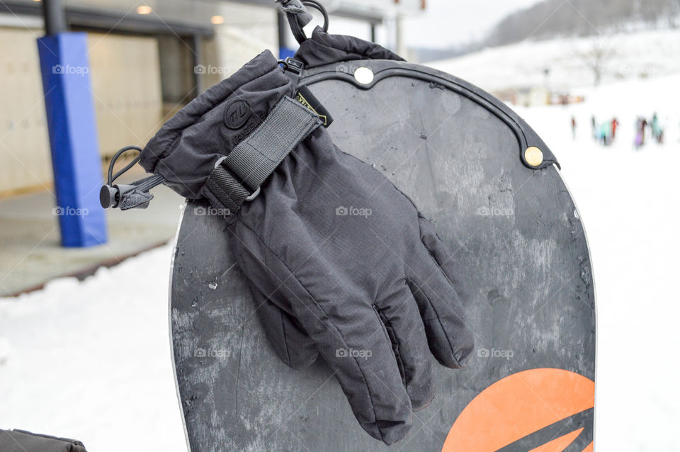 Winter gloves hanging from a snowboard outdoors