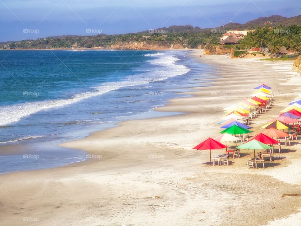 Relaxing on the Beach . Colorful umbrellas line the sand
