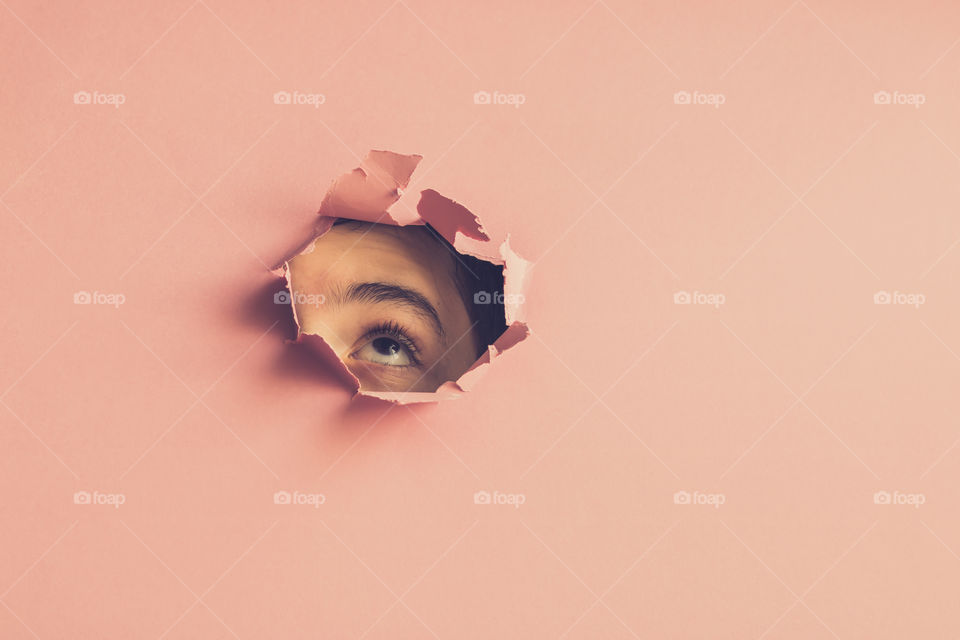 Abstract image of a child looking up through hole in paper background. Copy space.