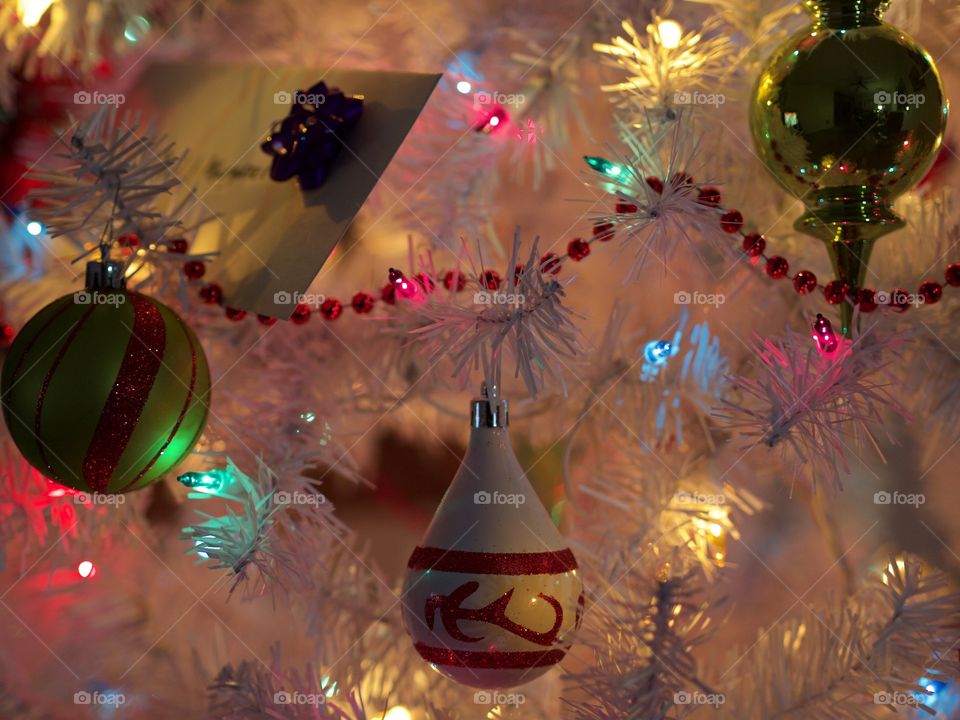 Ornaments hanging from a Christmas tree with a peaceful glow during the holiday season. 