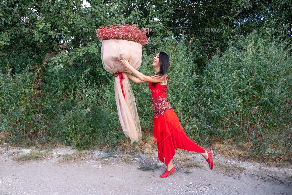 Woman Dances with a Large Bouquet of Red Flowers