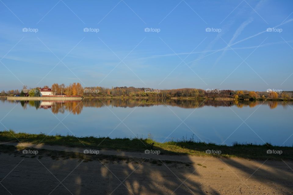 beautiful landscape lake and trees in the sunlight and shadows blue sky background autumn time