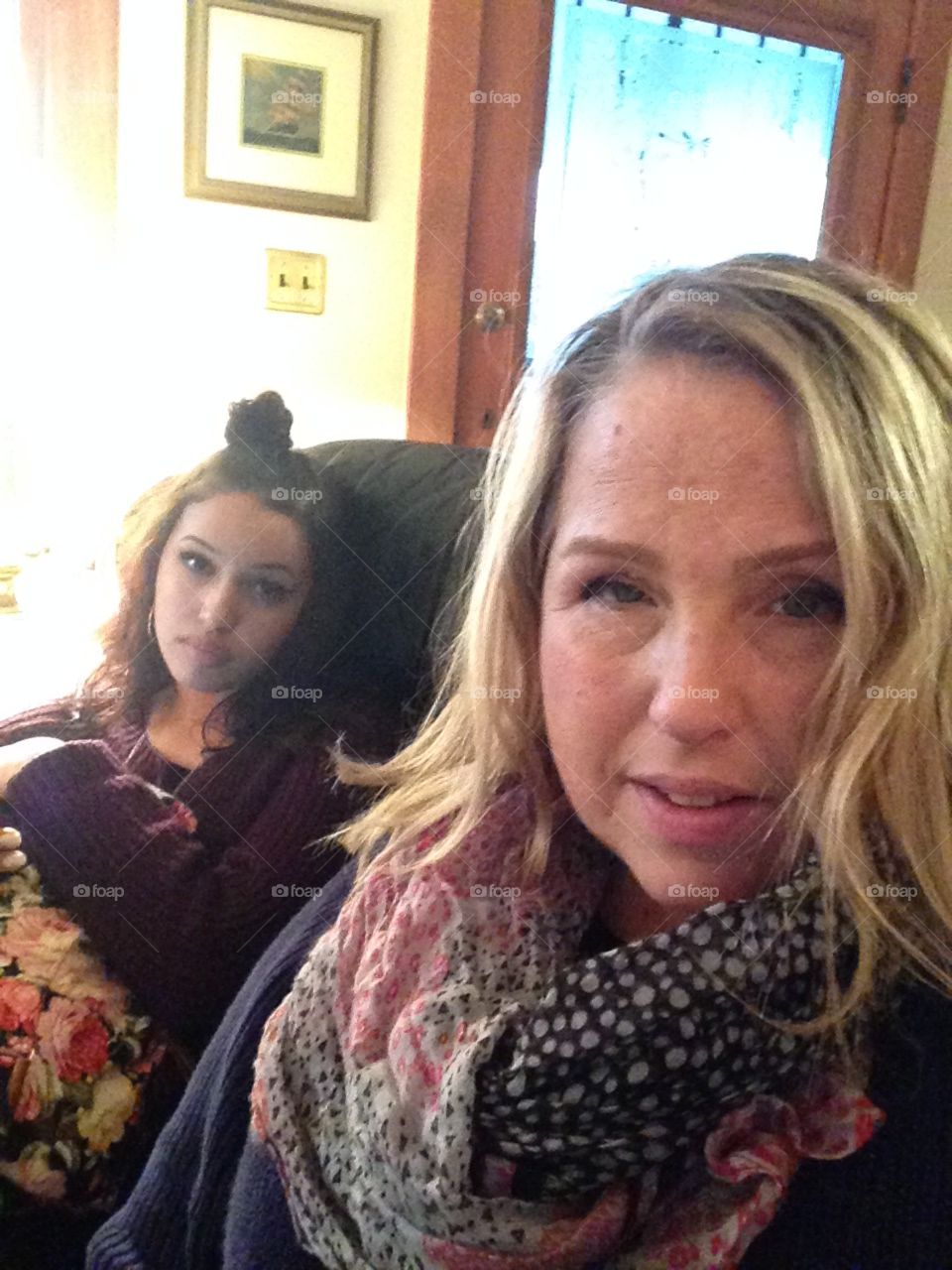 Mother and daughter sitting on sofa looking at the camera