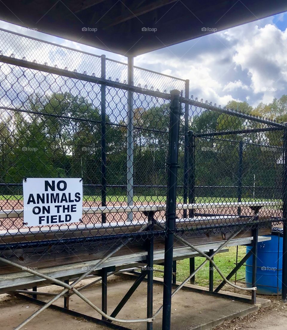 Sign on metal fence at baseball park 