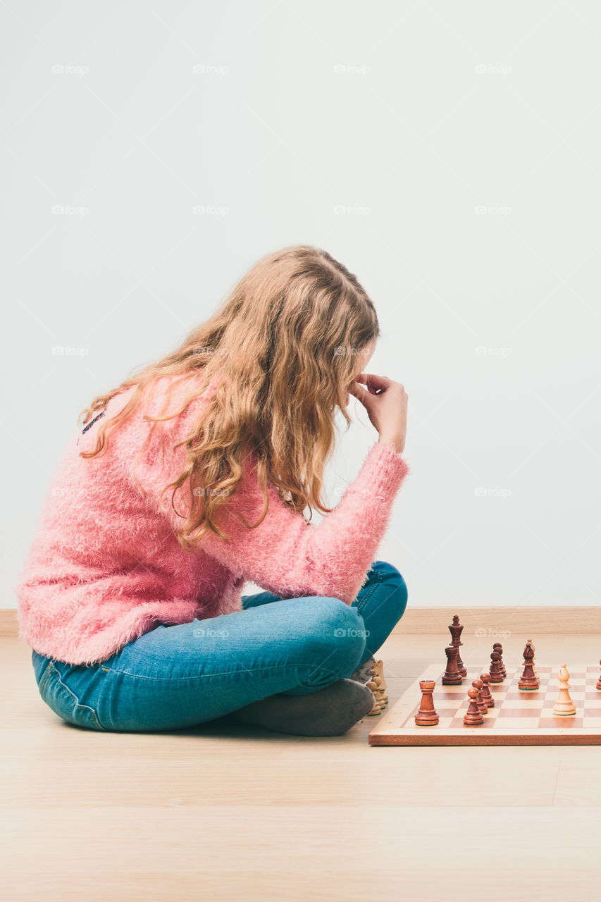 Girl deeply thinking about next move during chess game. Copy space for text at the top and bottom of image