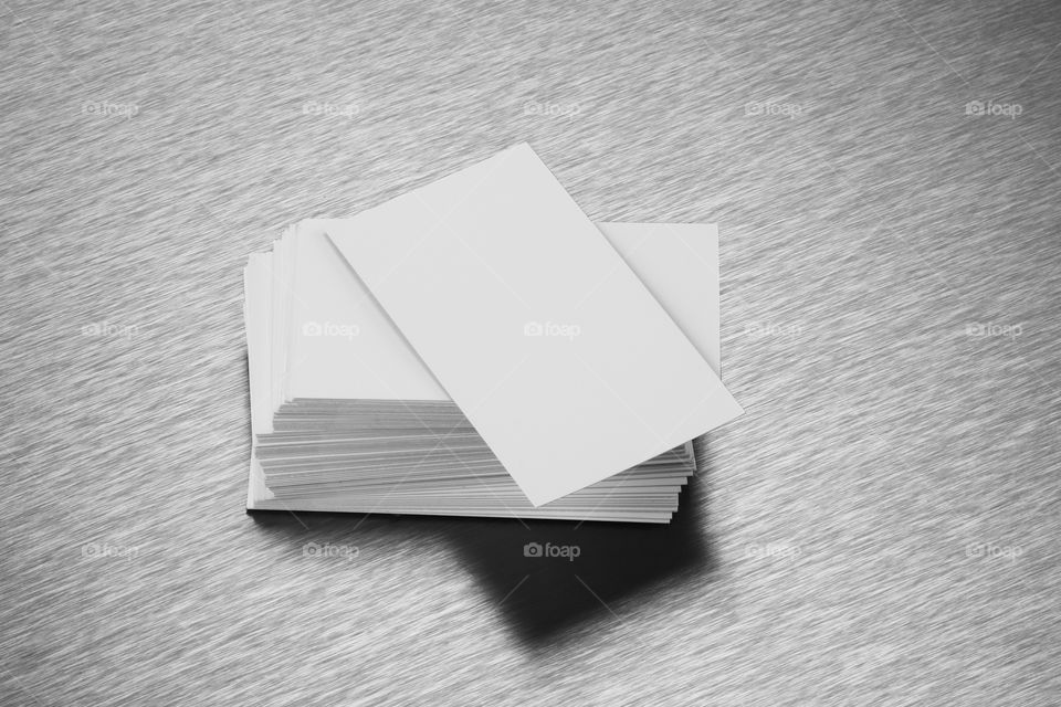 Blank white business cards on brushed steel background