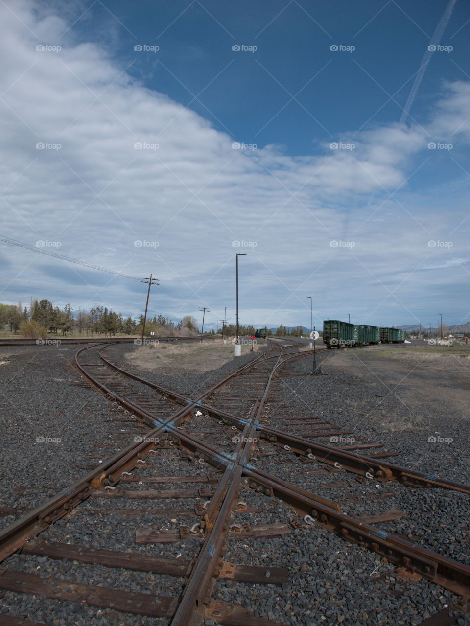 A few abandoned train cars on tracks that criss-cross each other on a sunny spring day in Central Oregon. 