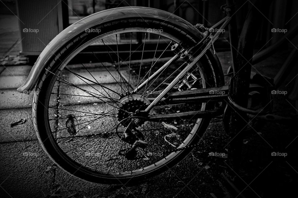 Lonely bicycle chained outside, bike wheel in black and white, monochrome bicycle image, bike out on the streets in England 