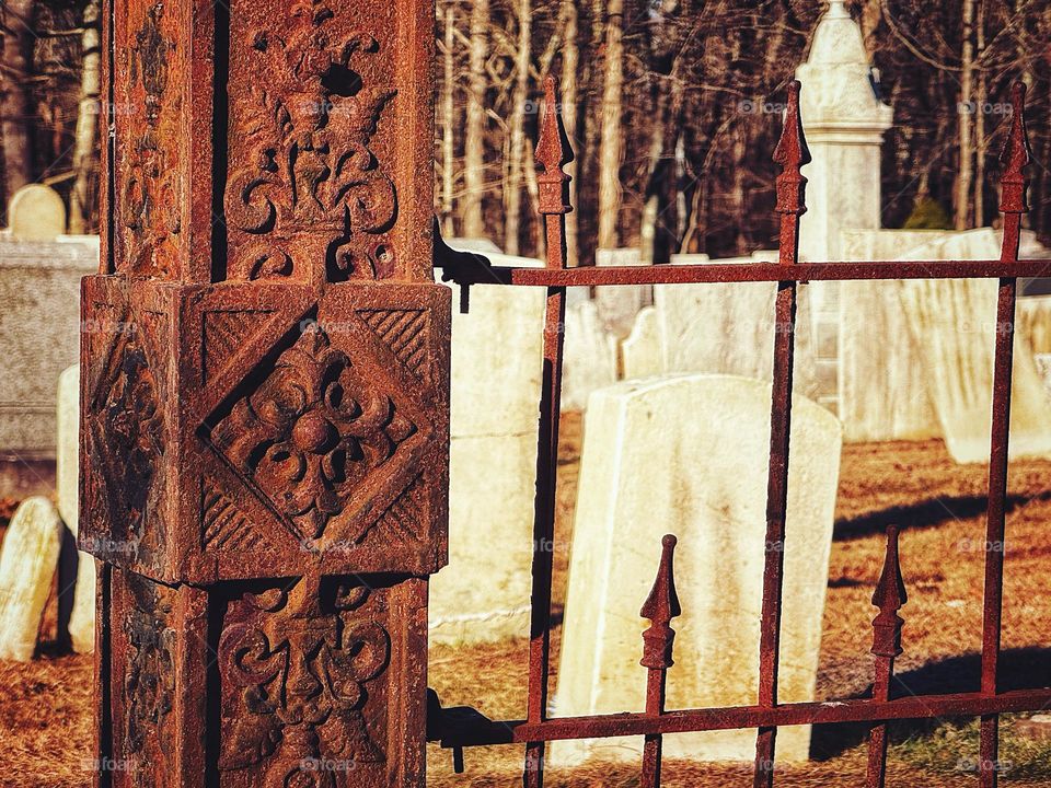 Rusted metal gatepost at a cemetery 