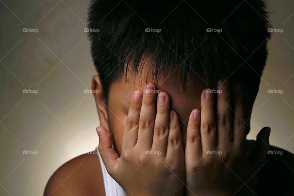Close-up of a boy covering his face with hands