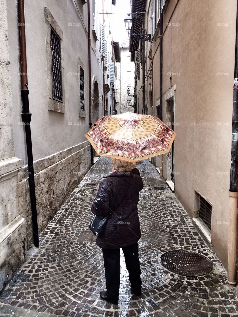 Old woman with umbrella, alley view