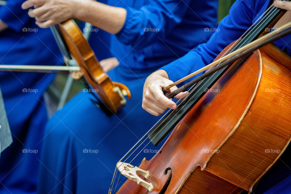 Soft focus. Woman in blue costumes play cello and violin.