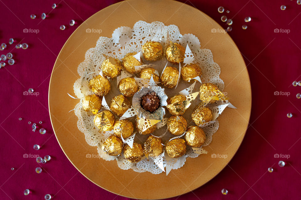 Ferrero Rosher chocolate in golden wrapping on golden plate.