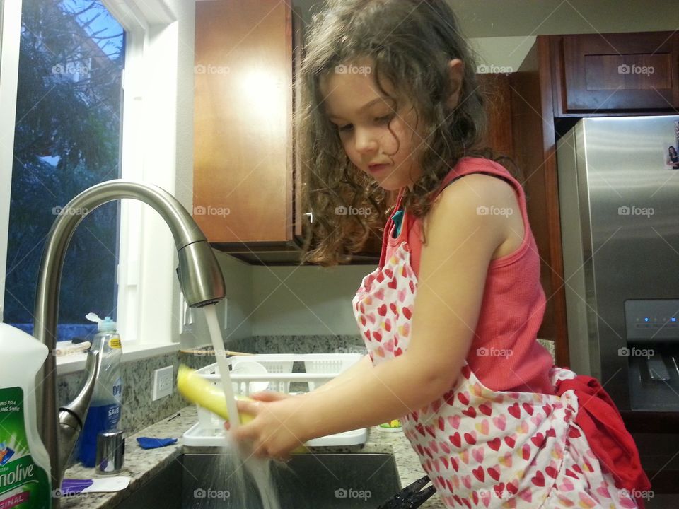 Dinner time. Baby girl washing squash for dinner. 